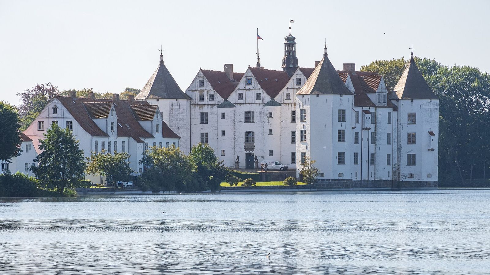 Das weiße Wasserschloss Glücksburg mit seinen vier Ecktürmen, gespiegelt im Schlossteich