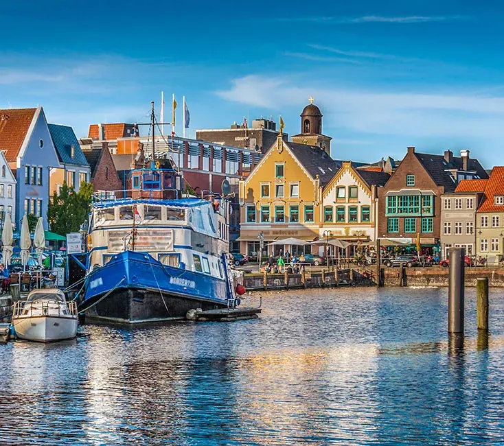 Day trip Husum — colourful gabled houses around the inner harbour with fishing cutters and sailing boats