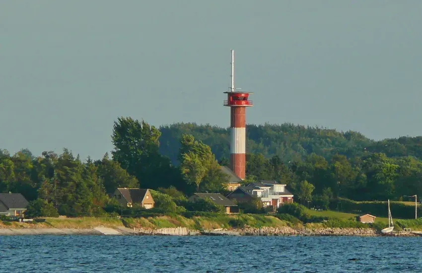 Leuchtturm Holnis — rot-weiß gestreifter Turm über bewaldeter Küste an der Halbinsel Holnis bei Glücksburg