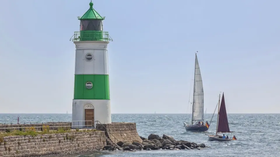 Leuchtturm Schleimünde — grün-weiß gestreifter Turm von 1871 auf der Lotseninsel mit zwei Segelbooten auf der Ostsee