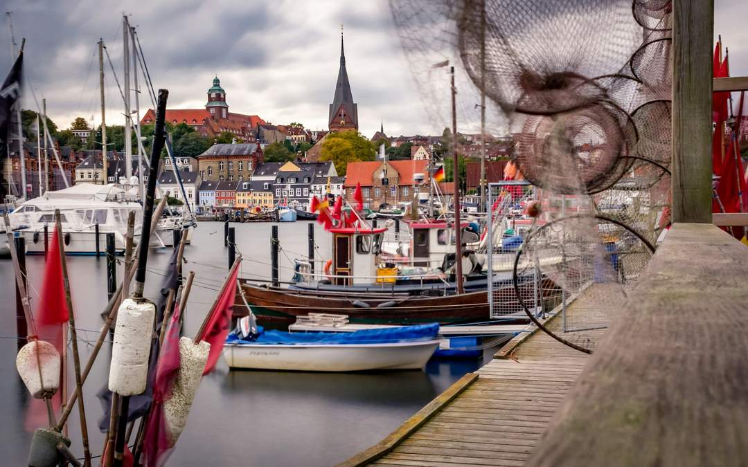 Historischer Flensburger Hafen mit Fischerbooten und Kirchturm im Hintergrund