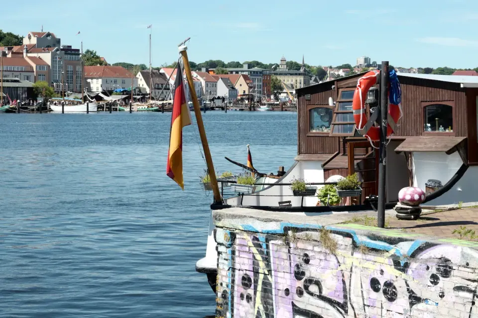Buntes Hausboot im Flensburger Hafen mit Stadtkulisse