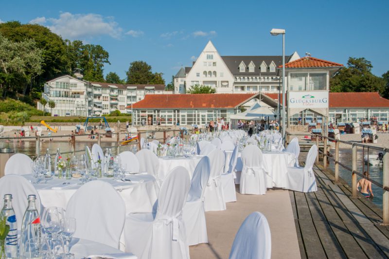 Festliche Tische auf der Seebrücke Glücksburg mit Strandhotel im Hintergrund