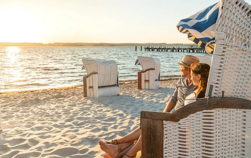 Paar im Strandkorb bei Sonnenuntergang am Strand von Glücksburg